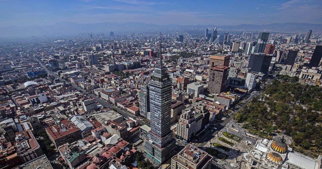 Panoramic view of the Mexico City skyline highlighting the iconic Torre Latinoamericana amidst a sea of buildings under a clear sky.